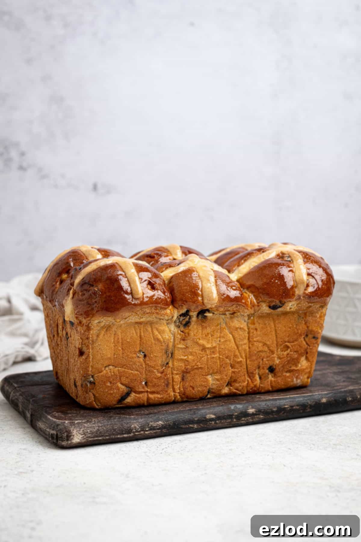 The baked vegan hot cross bun loaf on a wooden board.