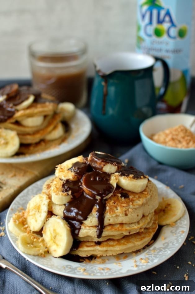 Toasted coconut pancakes with coconut milk chocolate fudge sauce and banana, a delicious, decadent breakfast or brunch (dairy-free)