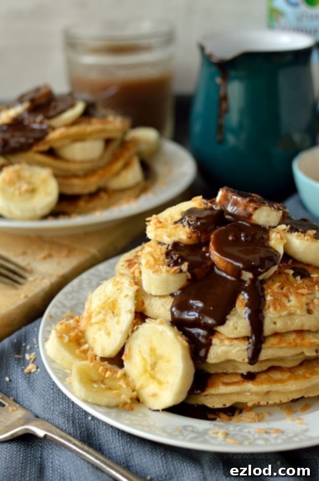Toasted coconut pancakes with coconut milk chocolate fudge sauce and banana, an utterly delicious and decadent breakfast or brunch (dairy-free)
