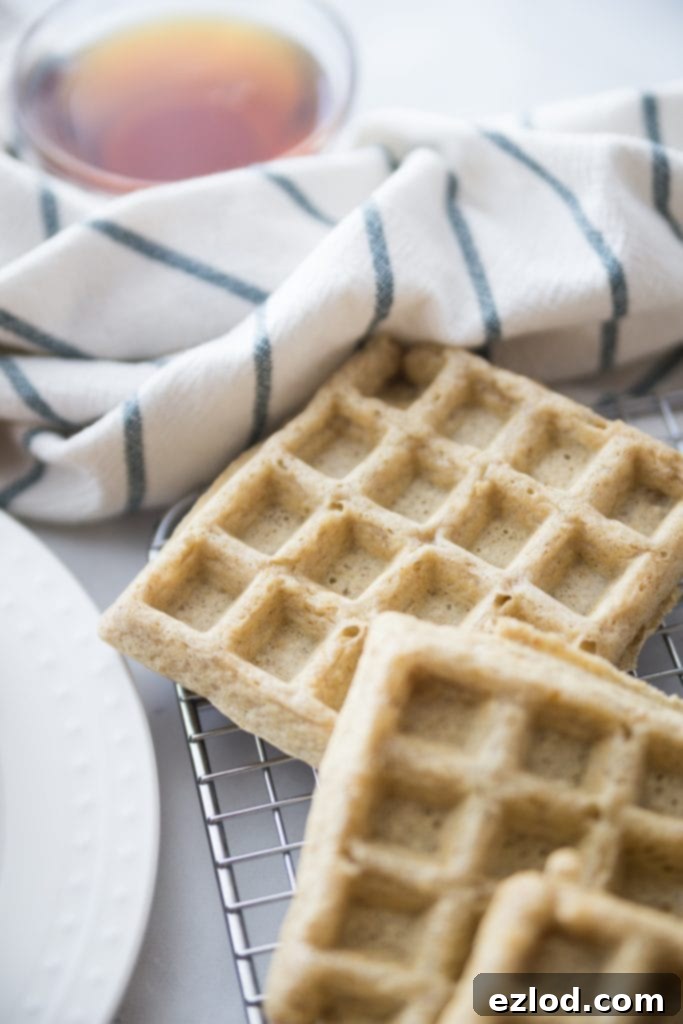 Gluten Free Make Ahead Freezer Waffles (2B Mindset/ 21 Day Fix) | Confessions of a Fit Foodie, stacked on a plate with fresh berries and syrup.