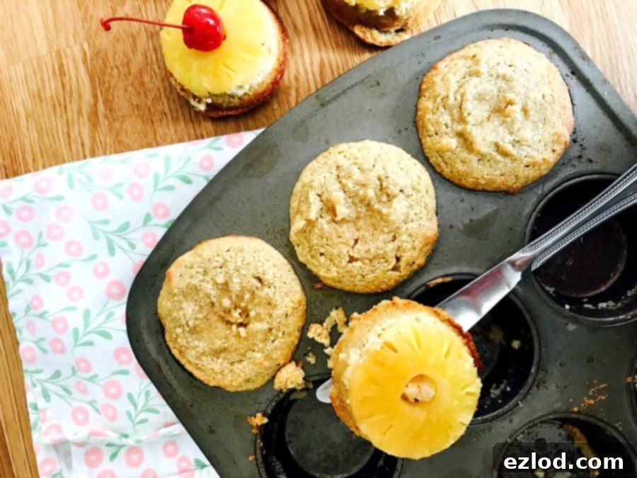 A knife removing pineapple upside down cupcakes from a muffin tin.