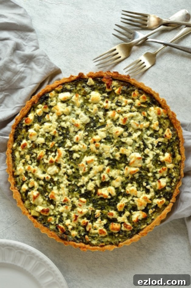 A top-down view of the freshly baked Spinach, Ricotta, and Feta Quiche, showing its golden-brown crust and evenly distributed, vibrant green filling.