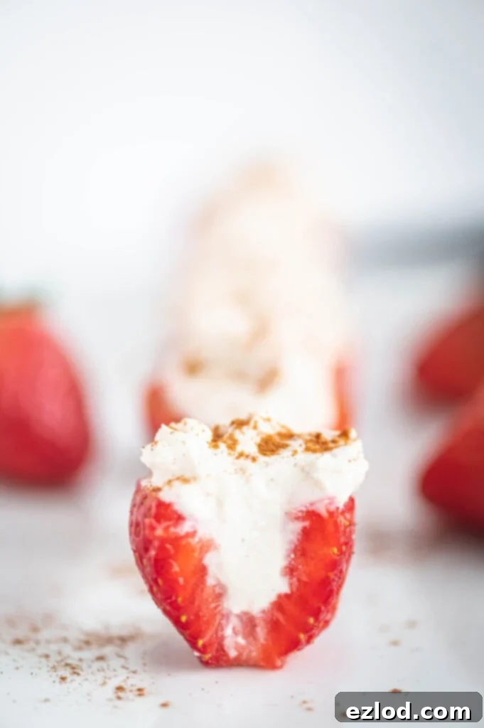 Side photo of a cross section of a cheesecake stuffed strawberry topped with cinnamon.
