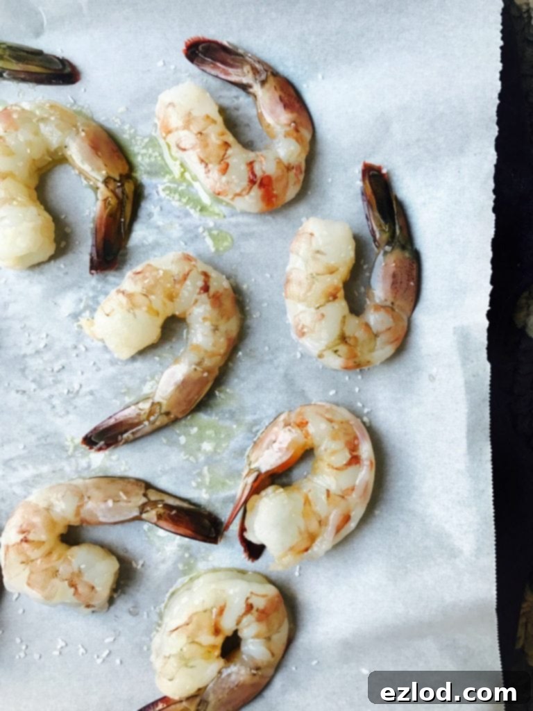 Raw shrimp drizzled with olive oil and salt on a parchment lined sheet pan