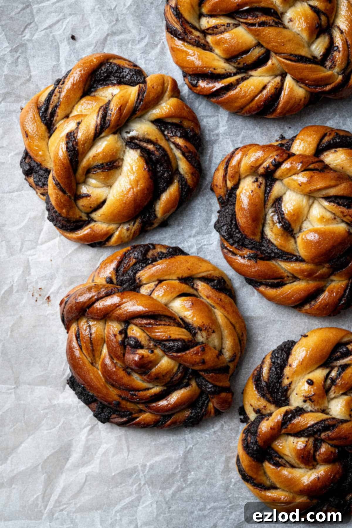 Vegan chocolate swirl buns on a sheet of baking paper.