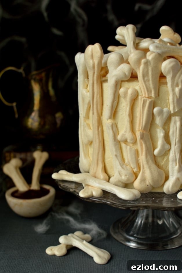 Meringue Bone Graveyard Halloween Cake - a gothic dessert with three layers of moist chocolate cake, vanilla Swiss meringue buttercream, raspberry jam, and an array of intricate meringue bones, drizzled with berry coulis 'blood'