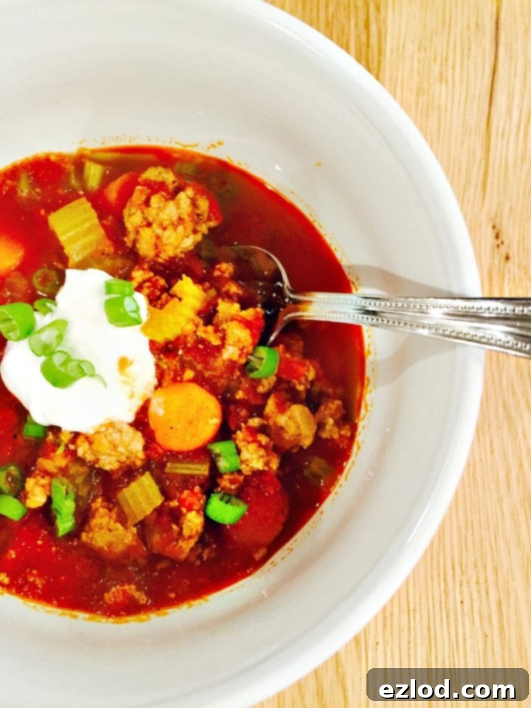 Overhead photo of buffalo chicken chili topped with blue cheese sauce and green onions