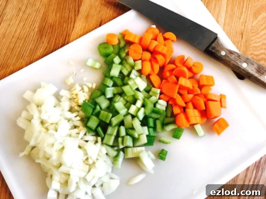 Chopped veggies on a white cutting board with a chef's knife on the side.