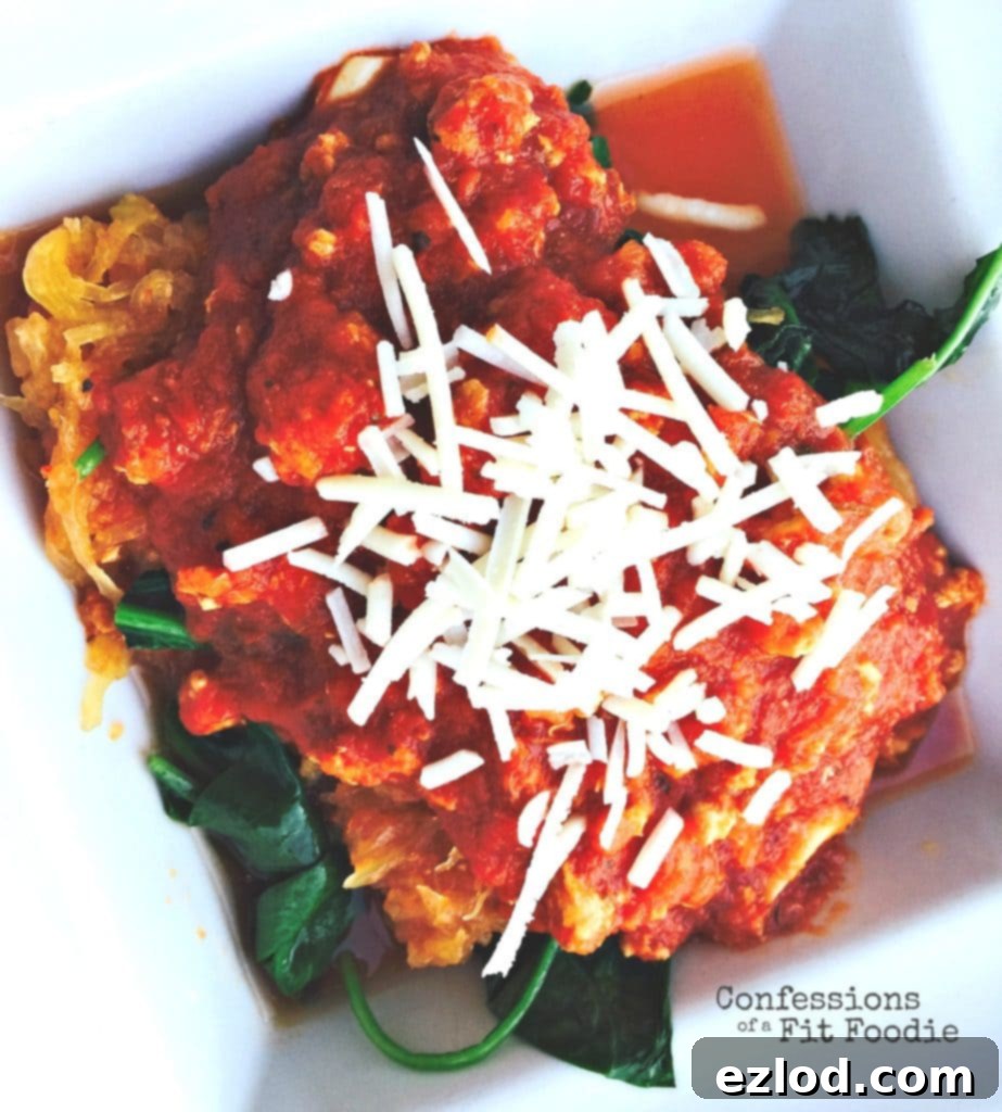Overhead photo of spaghetti squash topped with meat sauce, spinach, and shredded parmesan cheese.