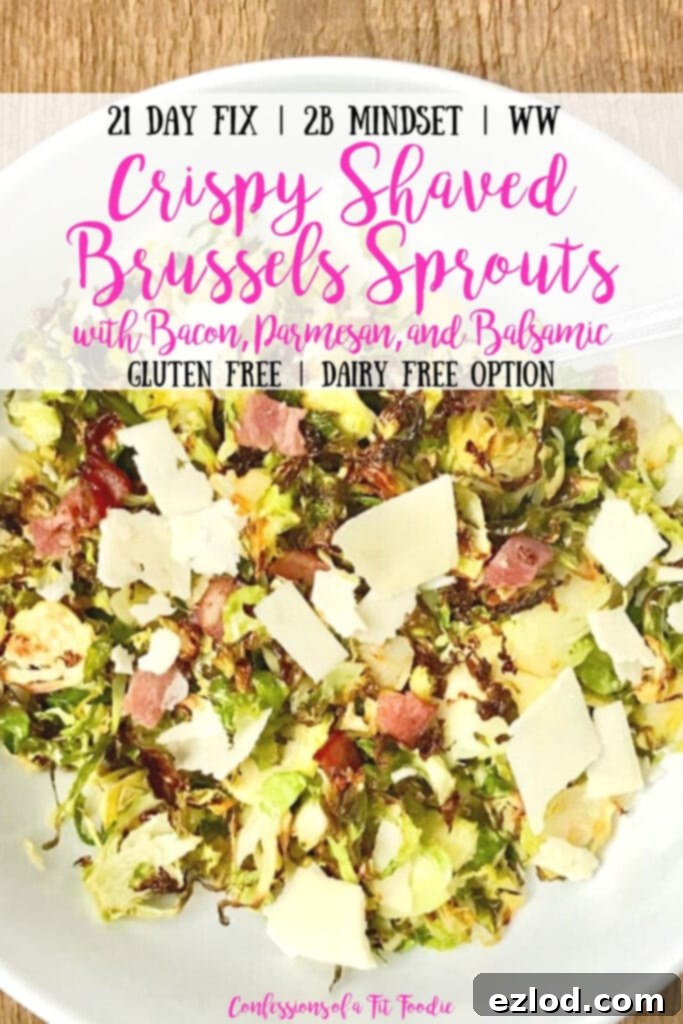 Overhead shot of a large white serving bowl with a silver spoon on a wooden surface. In the bowl is crispy shaved brussels sprouts topped with diced turkey bacon, shaved parmesan cheese, and a balsamic vinegar reduction. With the text overlay- 21 Day Fix | 2B Mindset | WW | Crispy Shaved Brussels Sprouts with Bacon, Parmesan, and Balsamic | Gluten Free | Dairy Free Option