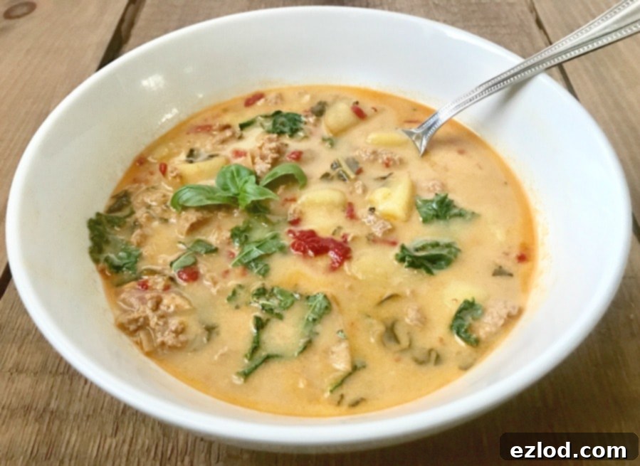 Close-up of a steaming bowl of 21 Day Fix Zuppa Toscana, showing the vibrant colors of kale, potatoes, and sausage in a creamy broth.