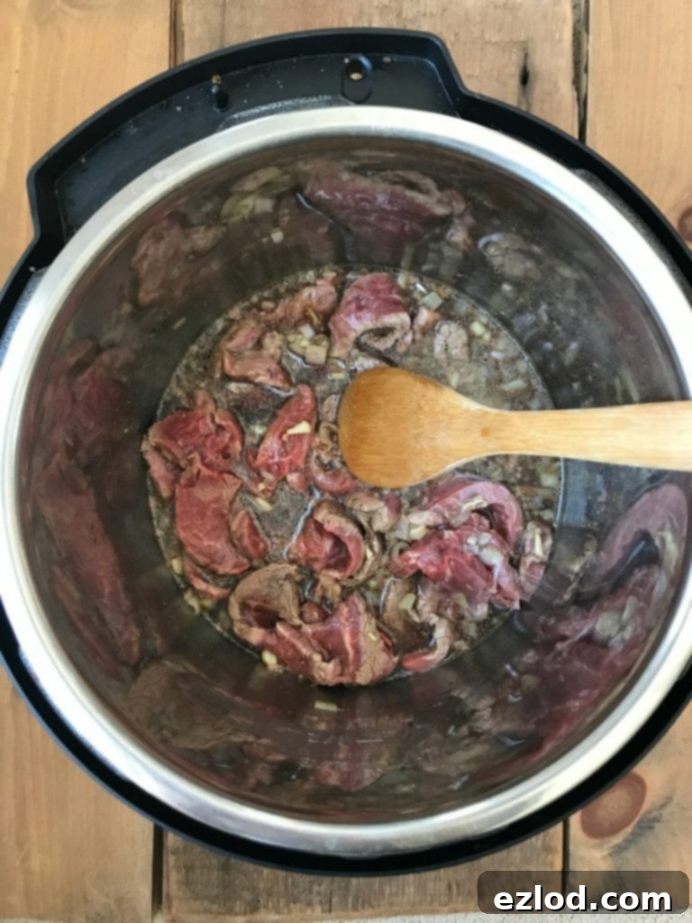 Fresh ingredients for Instant Pot Beef and Broccoli, including flank steak, shallots, garlic, and coconut aminos.