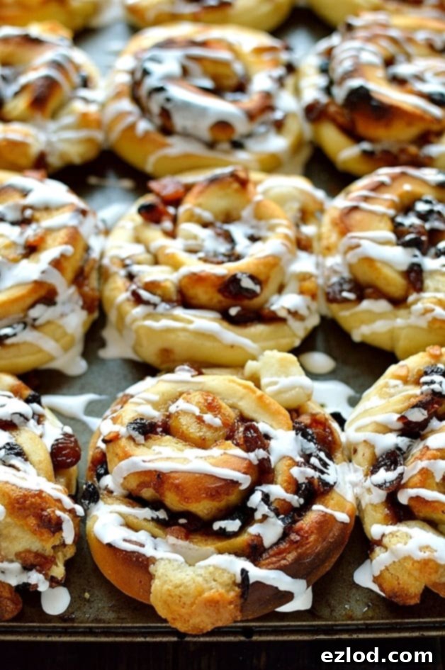 Freshly baked mincemeat and marzipan cinnamon buns cooling on a wire rack, ready for glazing.