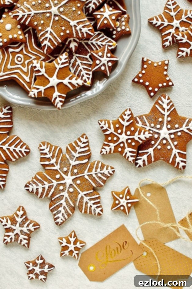 Assortment of festive gingerbread star and snowflake cookies, decorated with delicate royal icing designs.