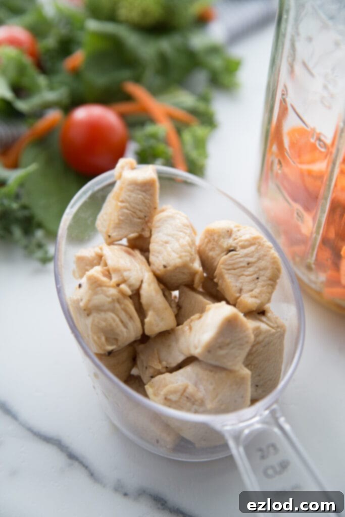 A measuring cup filled with cooked, diced chicken ready for assembly into a Mason Jar Salad, emphasizing meal prep efficiency.