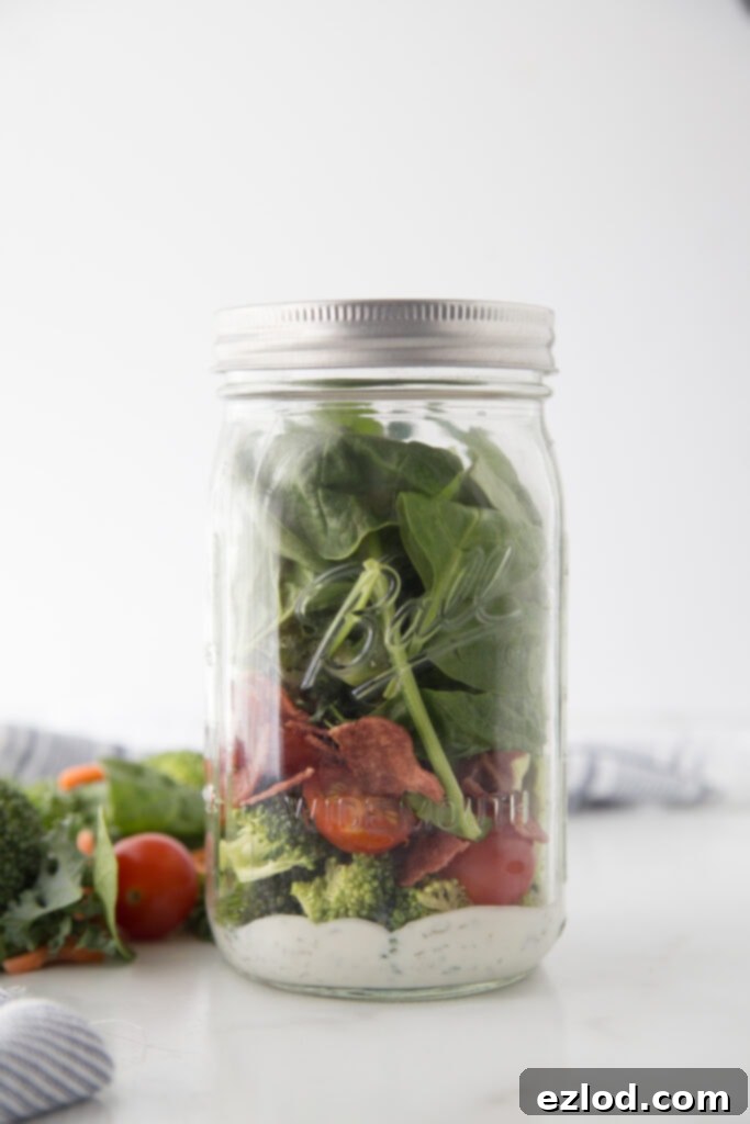 A large 24 oz wide-mouth mason jar partially filled with ranch dressing and hearty vegetables, illustrating the ideal size for a satisfying salad.