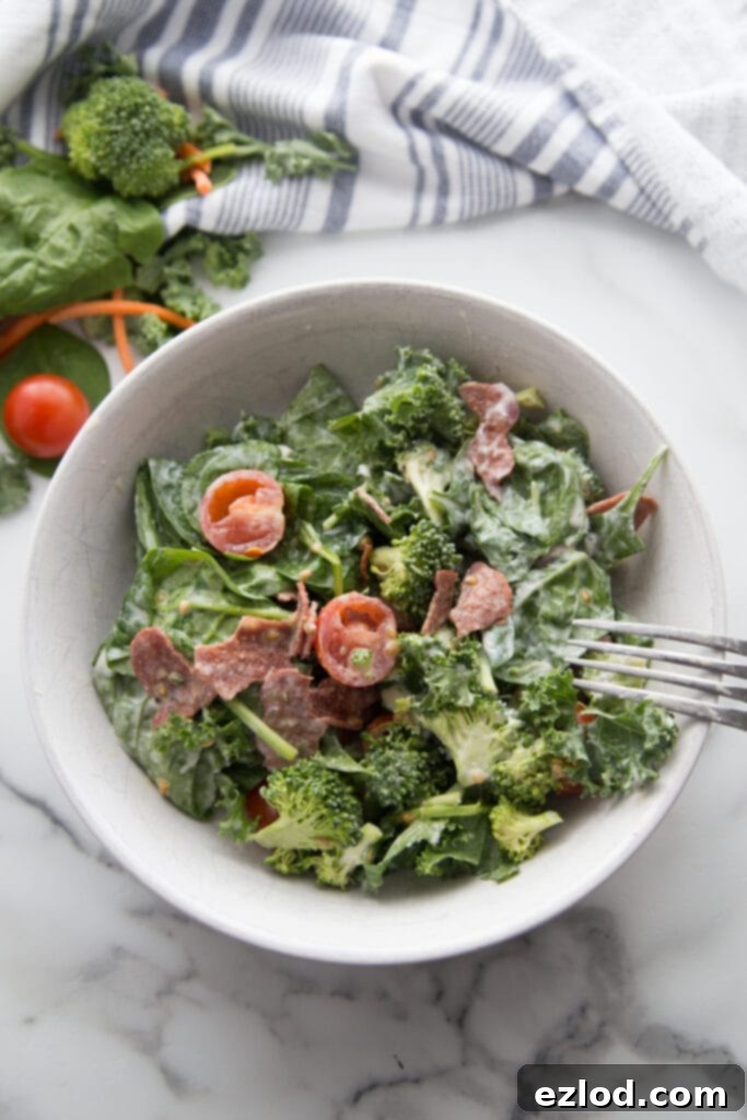 A vibrant bowl of BLT salad featuring fresh tomatoes, crispy bacon, mixed greens, and crunchy broccoli, freshly dumped from a mason jar.