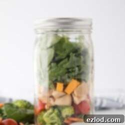 Two delicious Mason Jar Salads, one BLT and one Chicken Veggie Ranch, with a bowl of homemade ranch dressing.