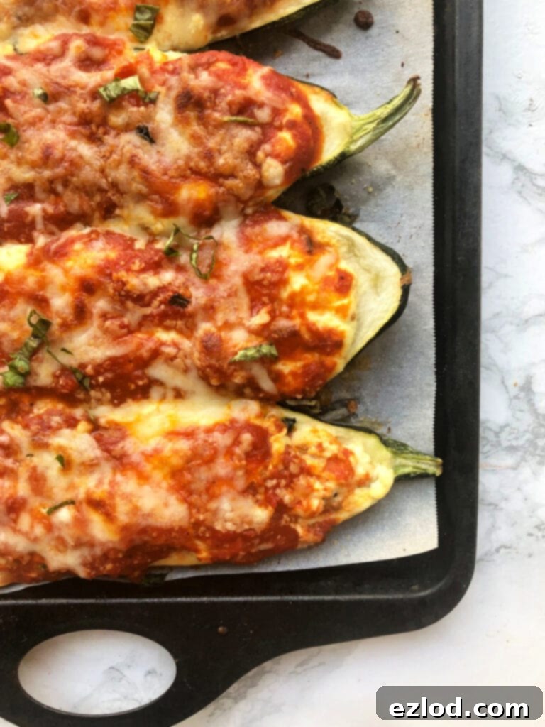 A baking sheet filled with golden-brown, bubbly, and crispy Lasagna Stuffed Zucchini Boats, freshly broiled and resting on an elegant marble backdrop, showcasing a perfect, cheesy finish ready to be served and enjoyed.