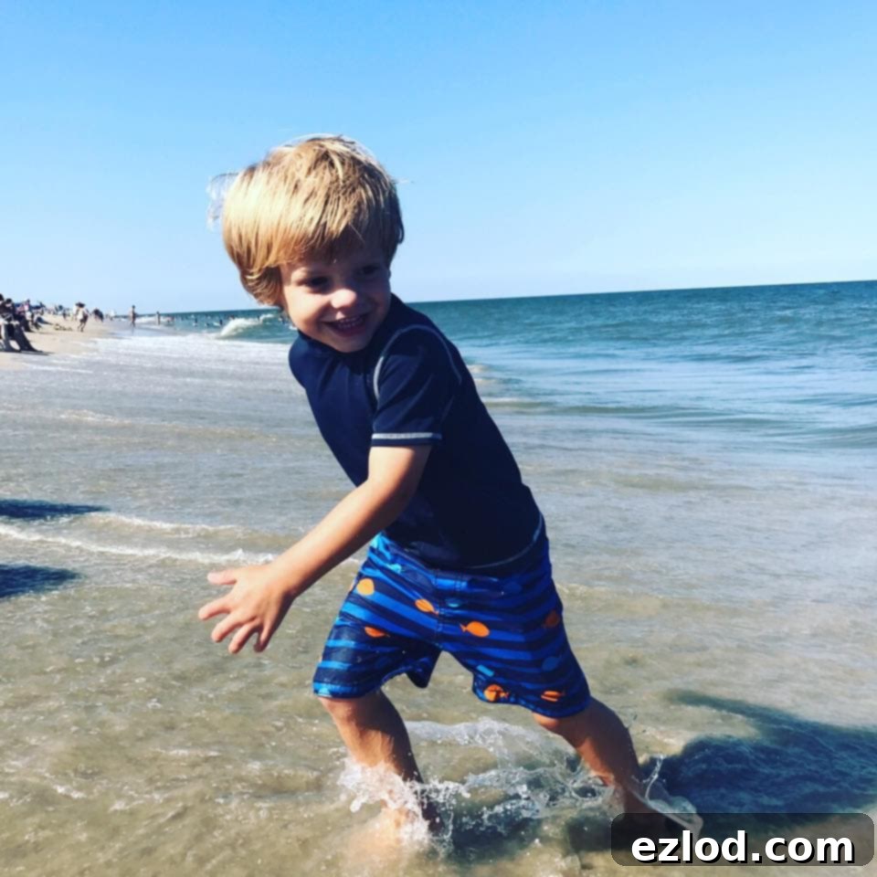 Max walking on a beach with an adult hand
