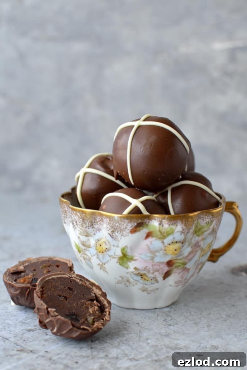 A stunning close-up of a Hot Cross Bun Chocolate Truffle, featuring its glossy dark chocolate shell, crisp white cross, and the hint of rich, spiced ganache within.