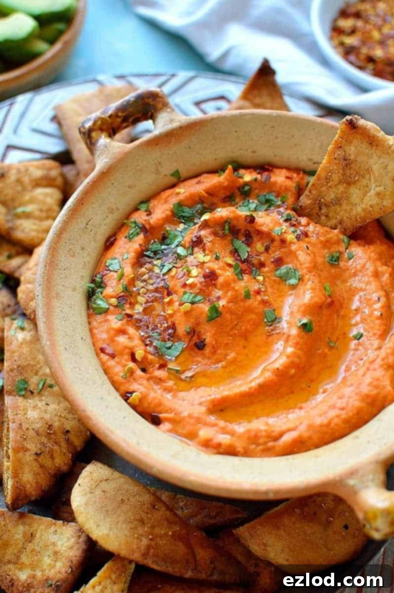 Roasted red pepper and chilli hummus with home-made seasoned pitta chips. Easy to make and the perfect snack!