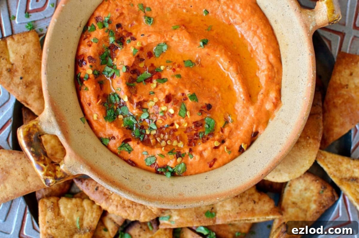 Roasted red pepper and chili hummus with home-made seasoned pitta chips. Easy to make and the perfect snack!