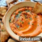 Roasted red pepper and chili hummus with home-made seasoned pitta chips. Easy to make and the perfect snack!