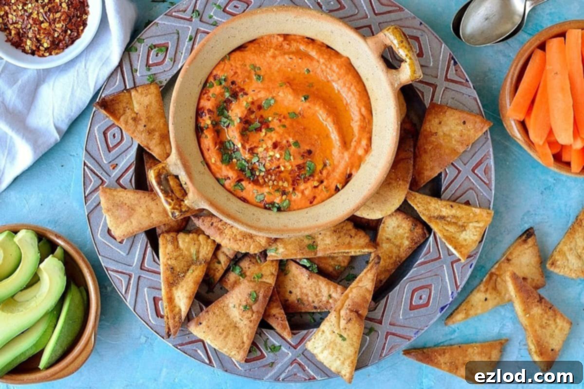 Roasted red pepper and chili hummus with home-made seasoned pitta chips. Easy to make and the perfect snack!