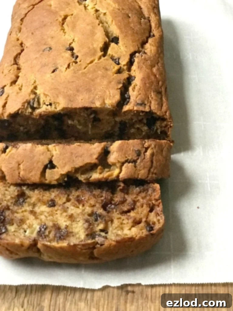 High angle photo of a loaf of healthy banana bread on a parchment lined wooden surface