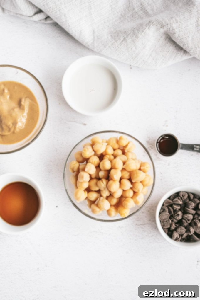 Various ingredients laid out for healthy chickpea cookie dough dip, including chickpeas, nut butter, chocolate chips, and sweeteners.