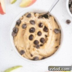 Close-up of a bowl of healthy edible cookie dough with a spoon, highlighting its creamy texture and chocolate chips.