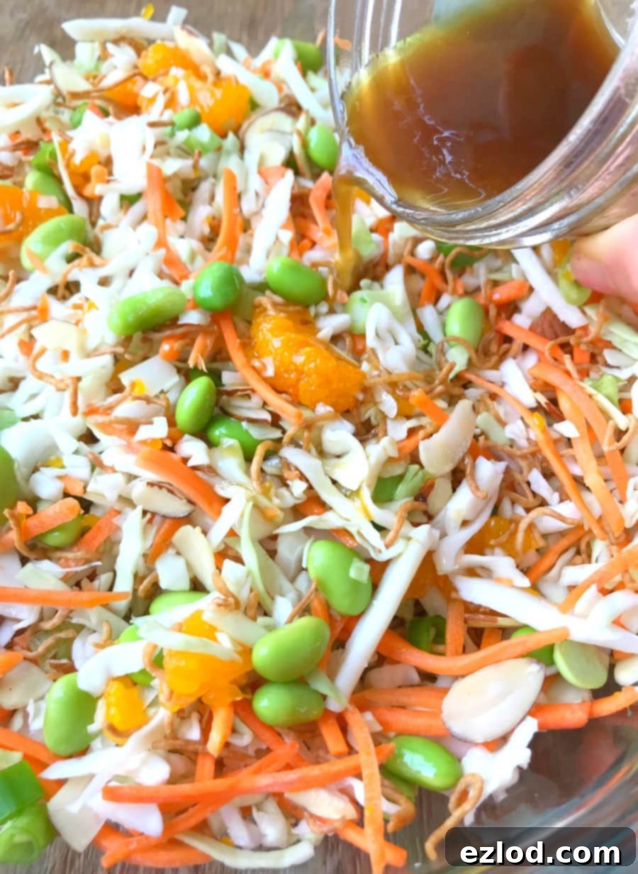 Close up photo of Ramen Noodle Salad with Asian Vinaigrette being poured over top from a glass mason jar