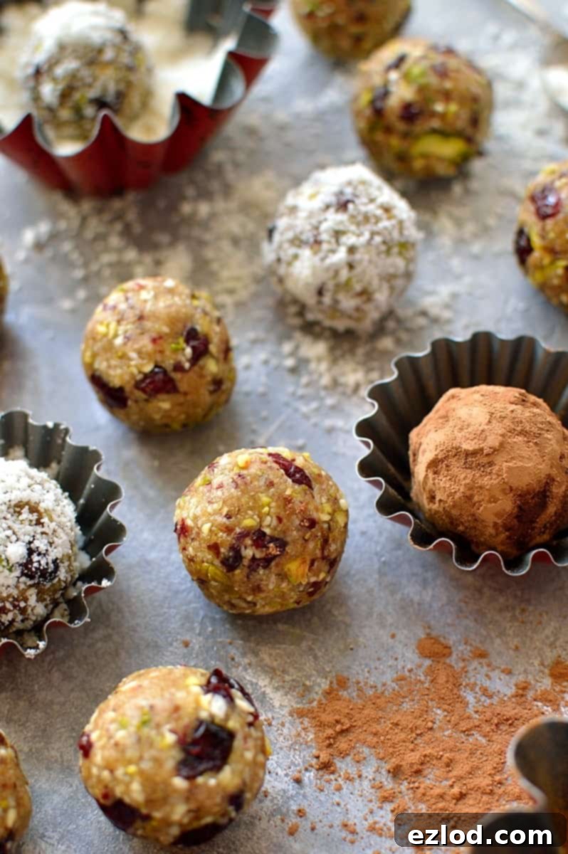 Several cranberry, pistachio, and coconut energy bites arranged on a wooden board, highlighting their vibrant colors and appealing texture, perfect for a quick and nutritious boost.