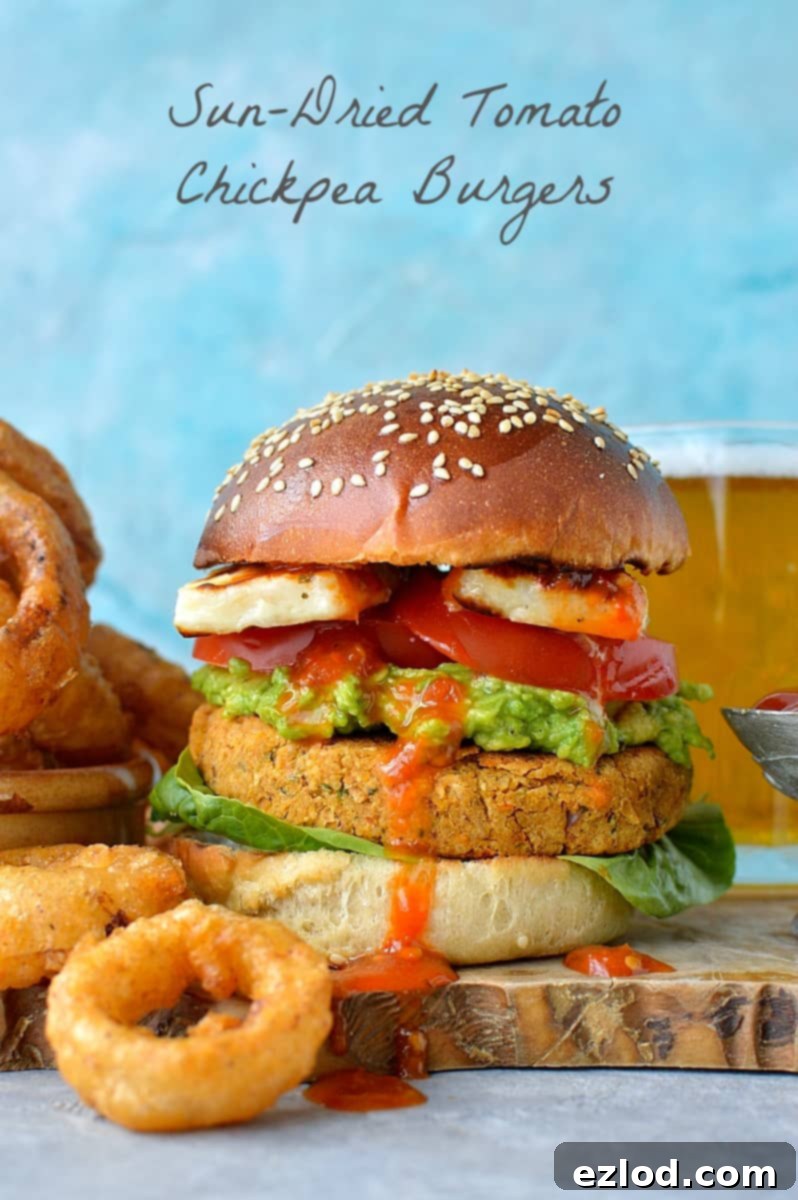 Close-up of a Sun-dried Tomato Chickpea Burger with Beer Battered Onion Rings, showcasing the delicious textures.