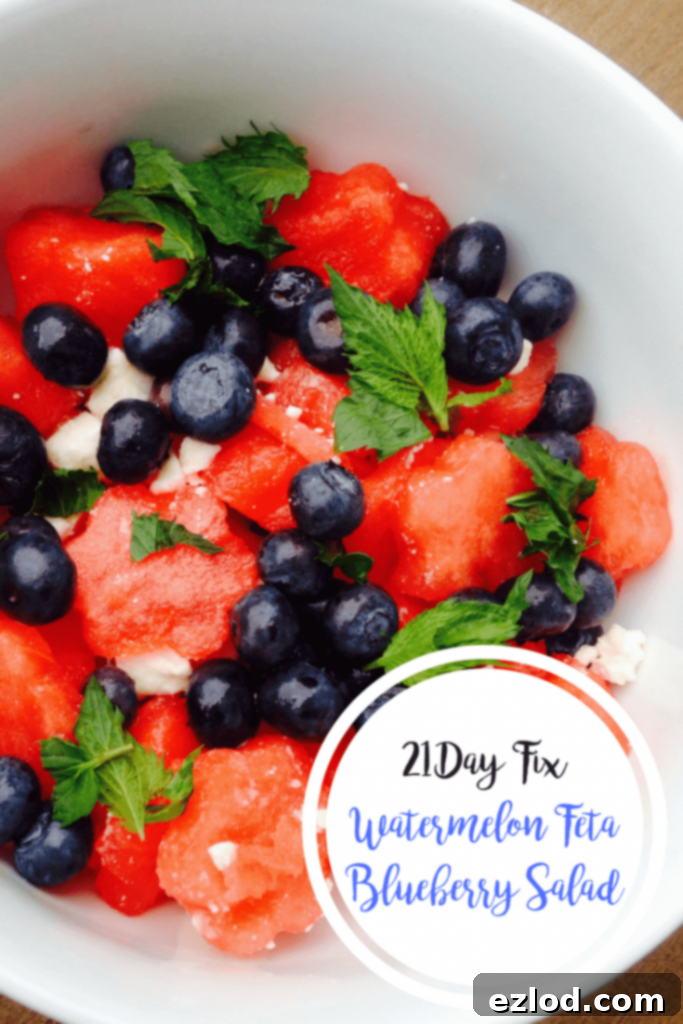 Watermelon, blueberries, feta, and mint mixed up in a white bowl with the text overlay- 21 Day Fix Watermelon Feta Blueberry Salad, perfect for healthy eating and summer BBQs.