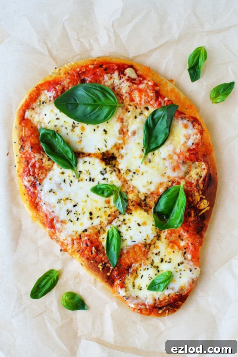 Two freshly baked naan pizzas on a baking sheet, showcasing their crisp edges and vibrant toppings.