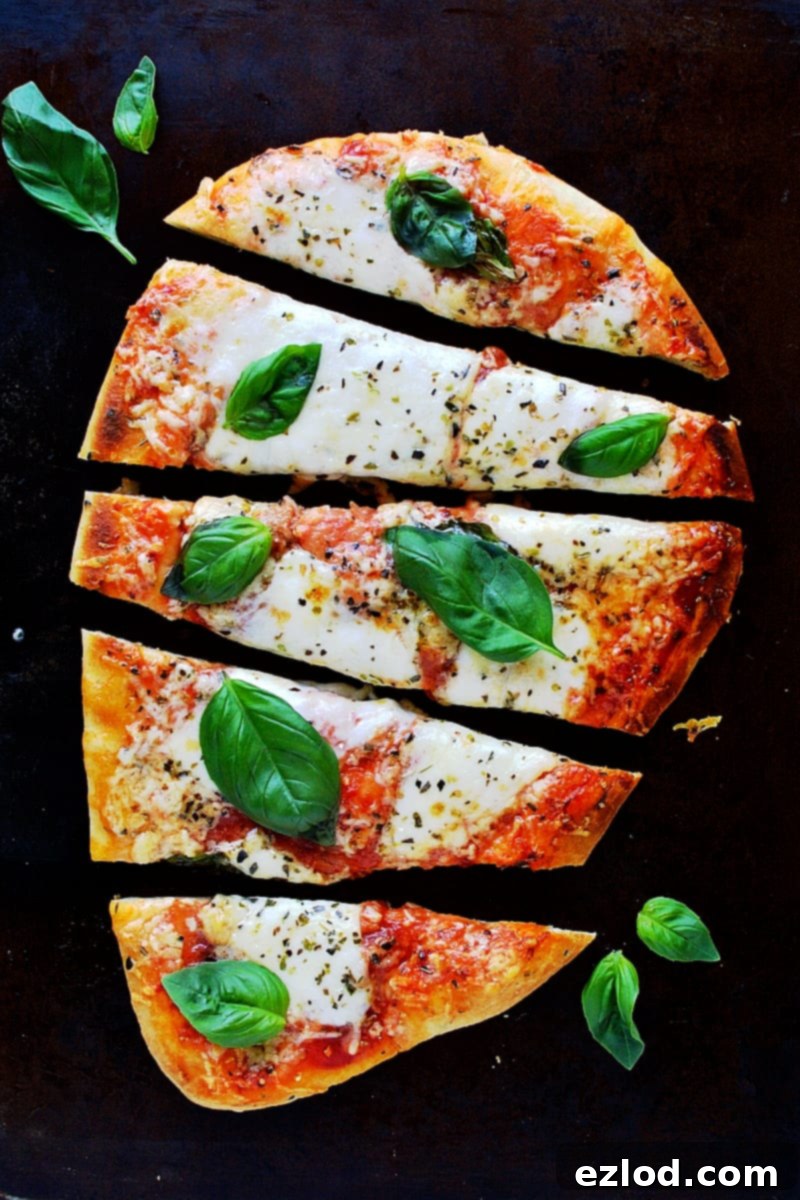 A slice of naan pizza being taken from the full pizza, showing the melted cheese and a crispy base.