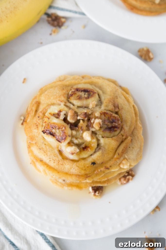 Pancake batter being poured over caramelized bananas and walnuts in a hot skillet, cooking to perfection.