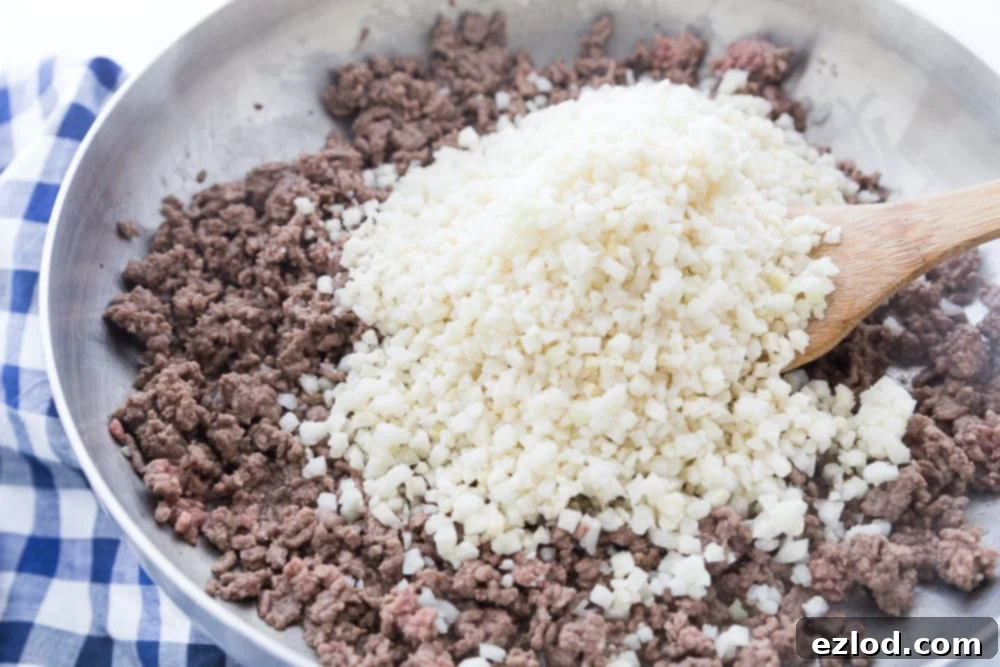 Two skillets of Hidden Cauliflower Taco Meat, one with raw cauliflower rice and the other with cooked meat and cauliflower.