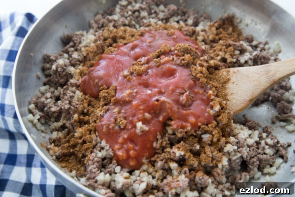 Hidden Cauliflower Taco Meat simmering in a skillet with tomato sauce and taco seasoning.