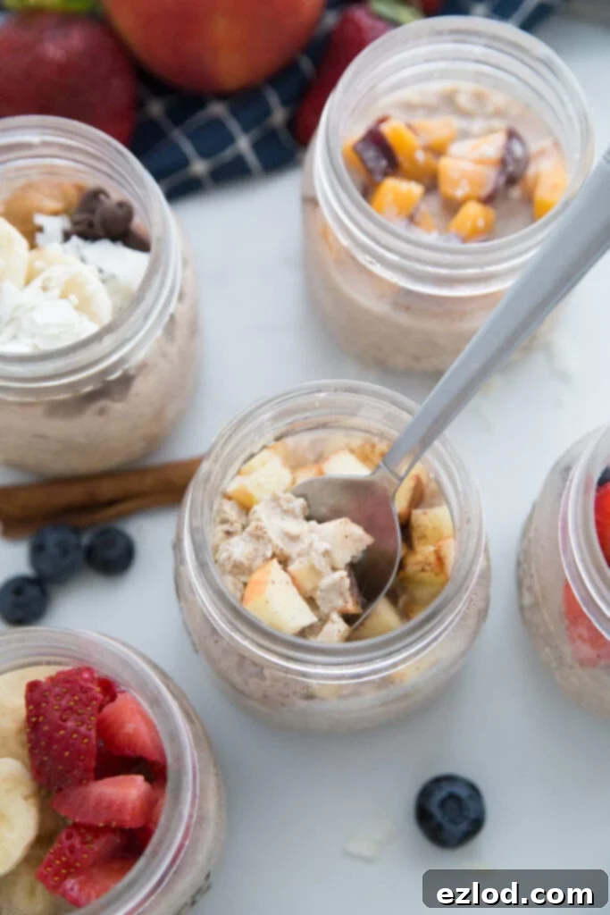 Overnight Oats in Mason Jars with 5 different toppings. The apple cinnamon one has a spoon inside.