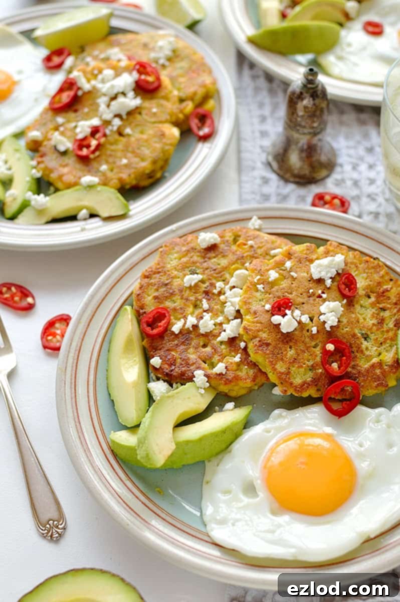 A stack of golden brown Sweetcorn and Feta Fritters, garnished with fresh herbs and a squeeze of lime, showcasing their inviting texture and appetizing color.