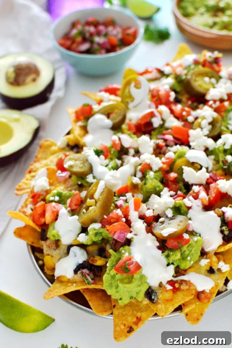 Loaded veggie nachos - topped with two kinds of beans, corn, salsa, guacamole, cheese and sour cream, this is the best way to eat a bag of chips for dinner!
