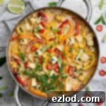 A pan of Thai style coconut tofu surrounded by herbs, lime slices and chillies.