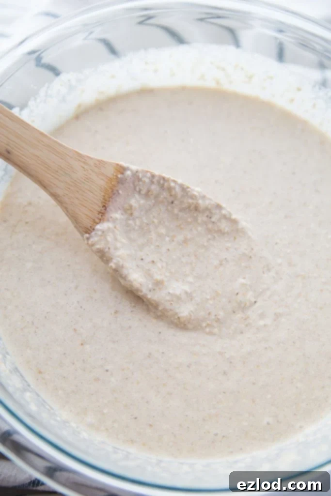 Waffle batter in a glass bowl with a wooden spoon