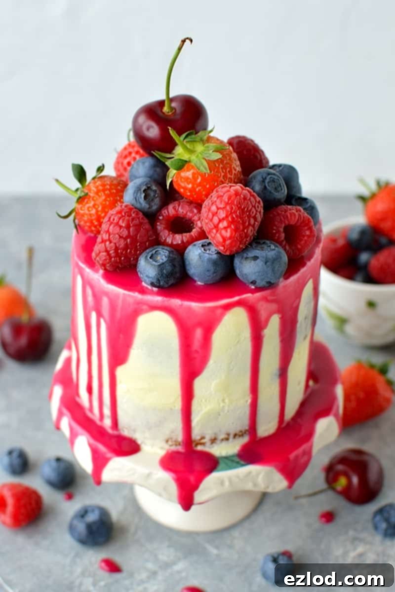 A beautifully decorated mini white chocolate berry drip cake, showcasing its delicate size and vibrant fresh fruit topping.