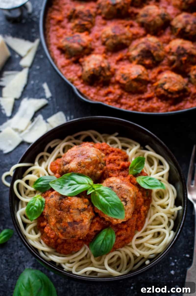 Vegetarian mushroom meatballs, tomato ragu sauce and spaghetti in a black bowl with basil leaves
