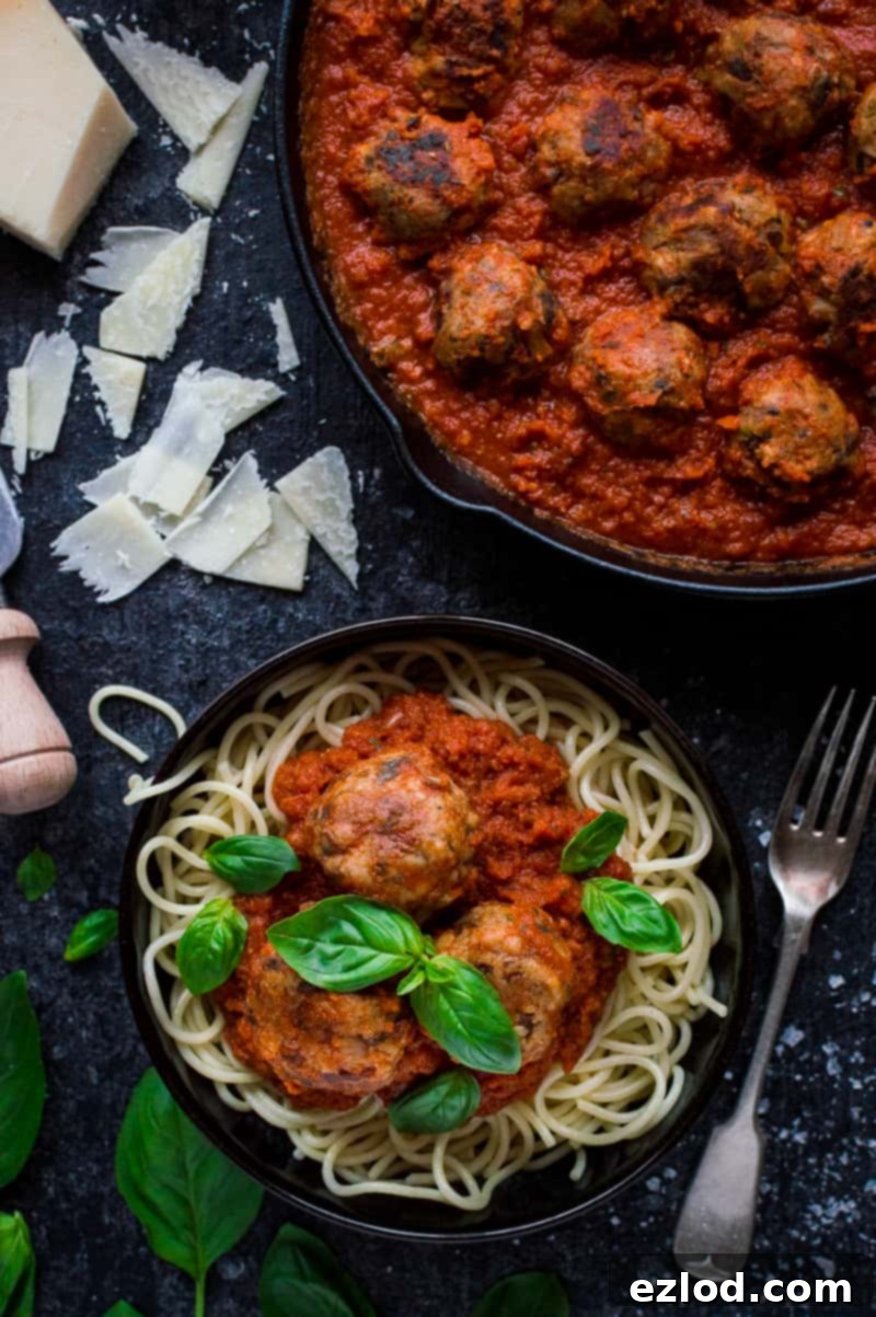 Vegetarian mushroom meatballs with tomato sauce, spaghetti, basil and cheese in a black bowl next to a skillet