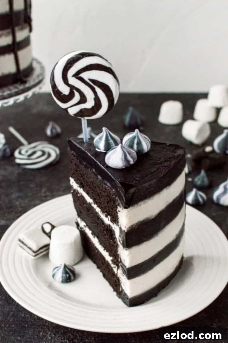 A slice of black and whitestriped monochrome chocolate and vanilla cake topped with a lollipop.